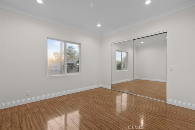 unfurnished bedroom featuring ornamental molding, a closet, and hardwood / wood-style floors