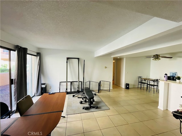 workout room with ceiling fan, light tile patterned floors, and a textured ceiling