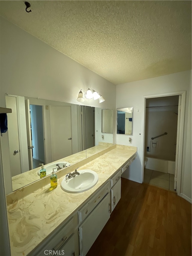 bathroom with a bathing tub, hardwood / wood-style floors, vanity, and a textured ceiling