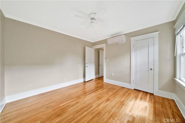 unfurnished bedroom with light wood-type flooring, ceiling fan, an AC wall unit, and multiple windows