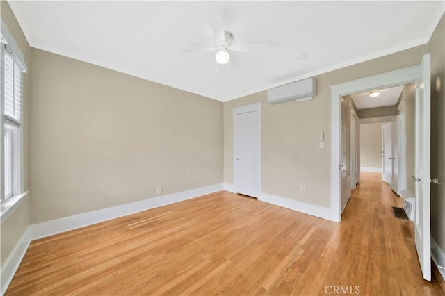 unfurnished room featuring ceiling fan, an AC wall unit, and light hardwood / wood-style flooring