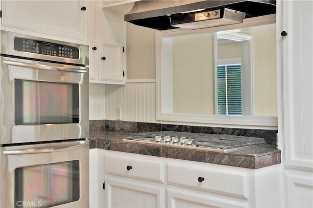 kitchen with extractor fan, stainless steel appliances, and white cabinetry