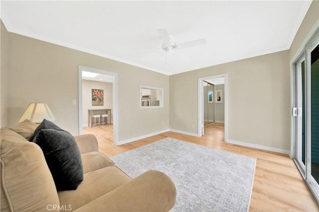 living room featuring ceiling fan, ornamental molding, and light hardwood / wood-style flooring