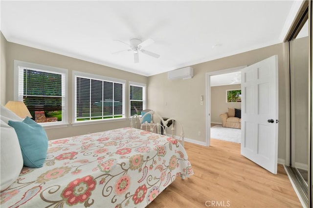 bedroom featuring ceiling fan, a closet, a wall unit AC, and light wood-type flooring