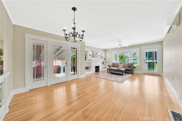 unfurnished living room featuring ornamental molding, light hardwood / wood-style floors, ceiling fan with notable chandelier, and french doors