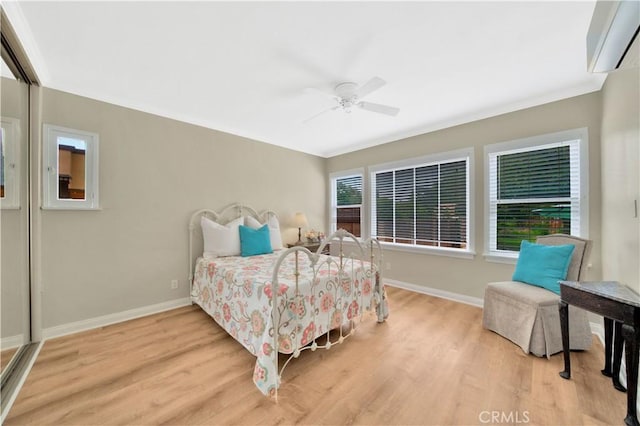 bedroom featuring a wall unit AC, ceiling fan, and light hardwood / wood-style floors