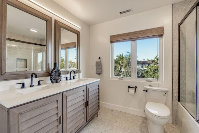 full bathroom featuring vanity, shower / bath combination with glass door, and toilet