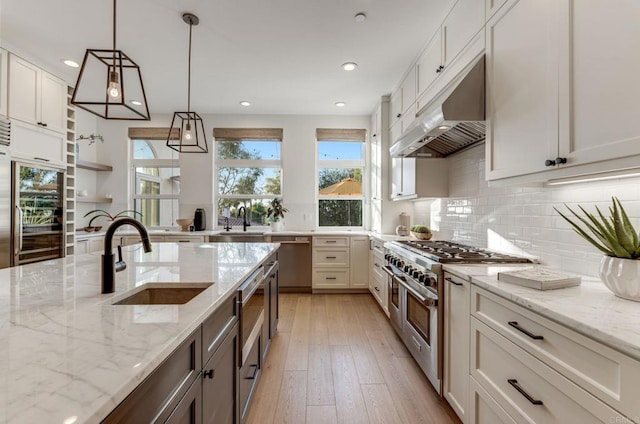 kitchen featuring sink, light stone counters, hanging light fixtures, appliances with stainless steel finishes, and white cabinets