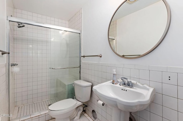 bathroom with walk in shower, tile walls, toilet, and sink