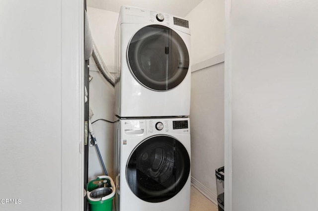 clothes washing area with stacked washing maching and dryer