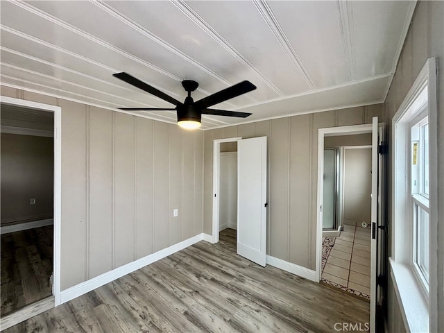 unfurnished bedroom featuring multiple windows, wood-type flooring, ceiling fan, and a closet