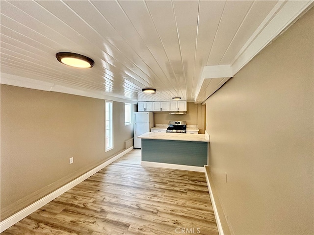 kitchen featuring light hardwood / wood-style floors, white refrigerator, stainless steel range oven, kitchen peninsula, and wooden ceiling