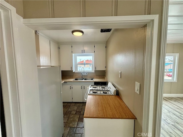 kitchen with white cabinets, butcher block countertops, sink, and white range oven