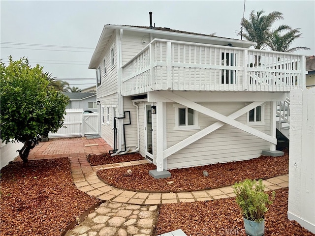 rear view of house with a wooden deck and a patio area