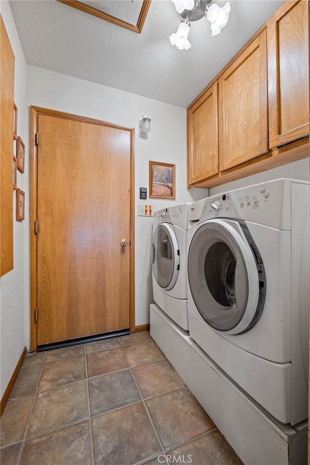 clothes washing area featuring a textured ceiling, washer and dryer, and cabinets