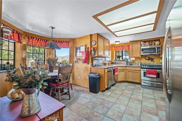 kitchen with appliances with stainless steel finishes, hanging light fixtures, a textured ceiling, and sink