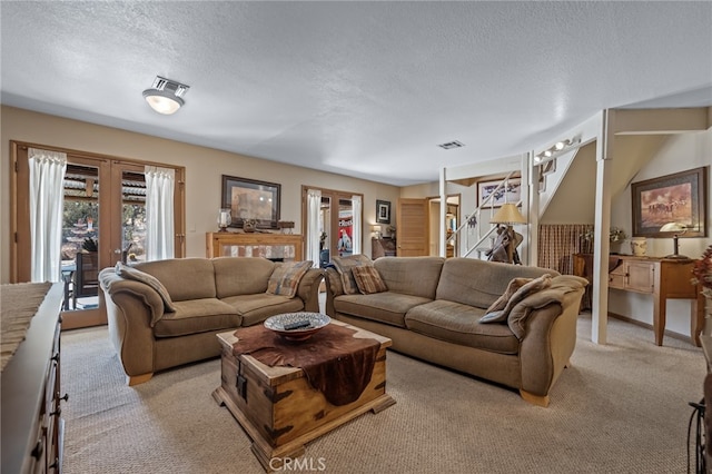 living room with a textured ceiling, light carpet, and french doors