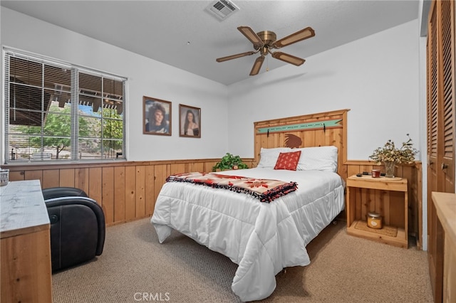 bedroom featuring wood walls, light carpet, ceiling fan, and a closet