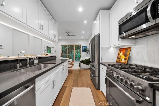 kitchen with light hardwood / wood-style floors, white cabinetry, high quality appliances, and sink