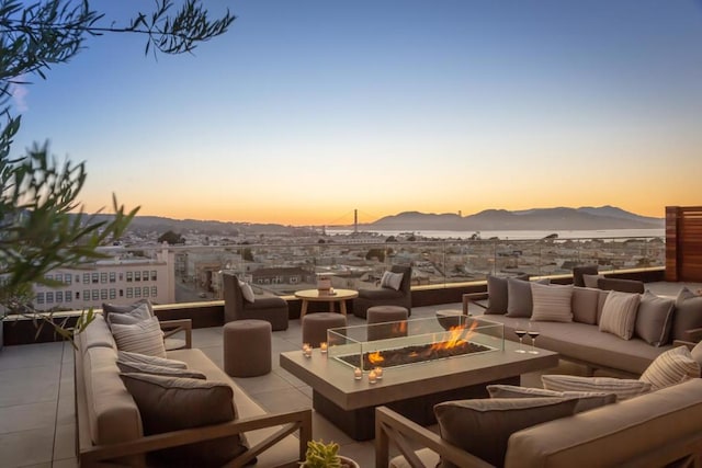 patio terrace at dusk with an outdoor living space with a fire pit and a mountain view