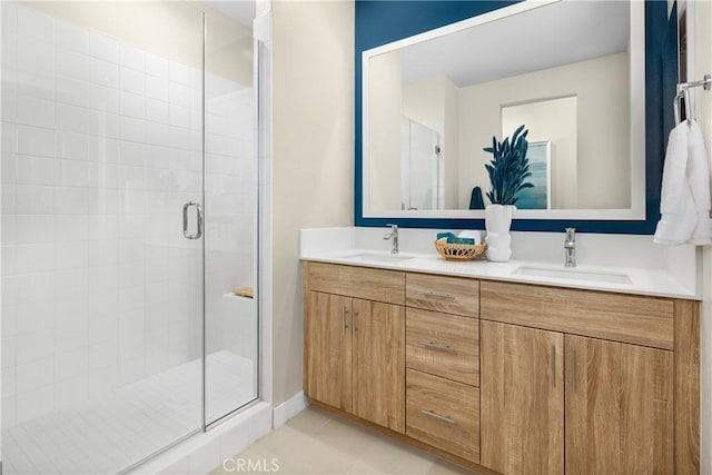 bathroom featuring double vanity, a stall shower, a sink, and tile patterned floors