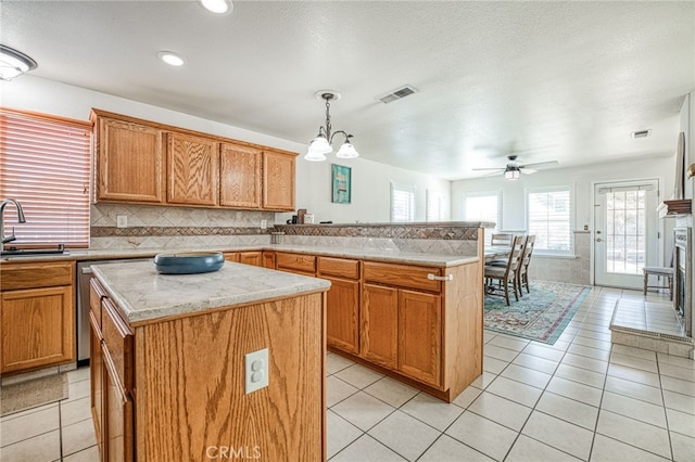 kitchen with backsplash, a center island, hanging light fixtures, and ceiling fan with notable chandelier