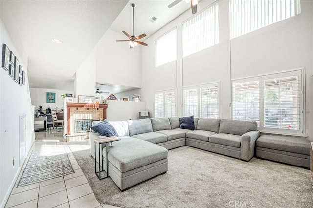 living room with ceiling fan, light tile patterned floors, and a high ceiling