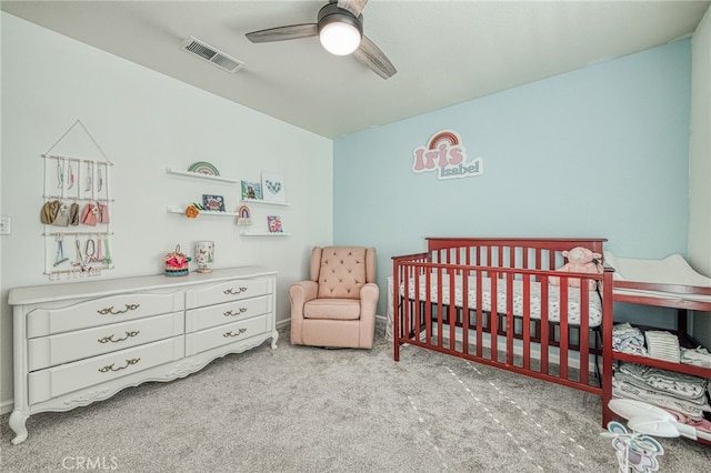 bedroom with ceiling fan, a nursery area, and light carpet