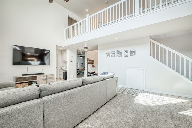 living room with a towering ceiling, carpet floors, and ceiling fan