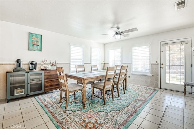 tiled dining area featuring a textured ceiling, ceiling fan, plenty of natural light, and tile walls