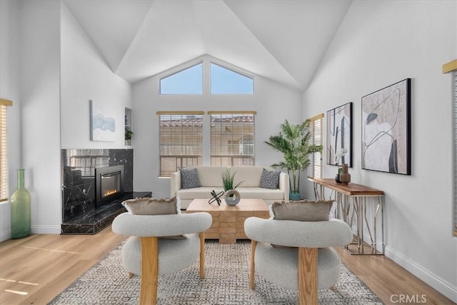 living room featuring a high end fireplace, wood-type flooring, and high vaulted ceiling