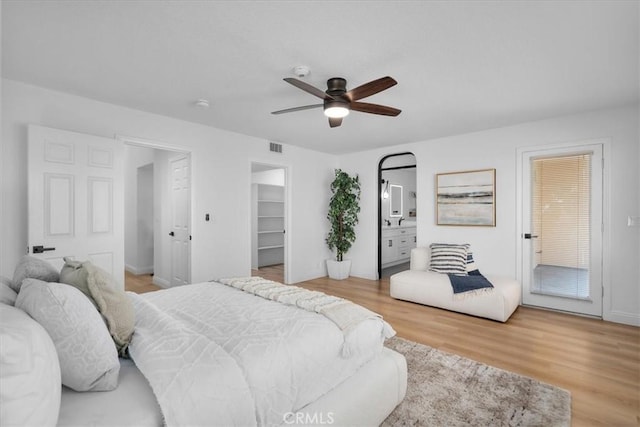 bedroom with connected bathroom, ceiling fan, hardwood / wood-style floors, a walk in closet, and a closet