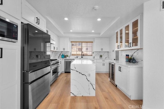 kitchen with white cabinets, a kitchen island, appliances with stainless steel finishes, and light hardwood / wood-style flooring