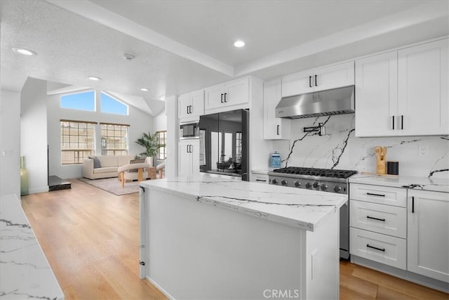 kitchen with high end appliances, lofted ceiling, white cabinets, light wood-type flooring, and light stone counters