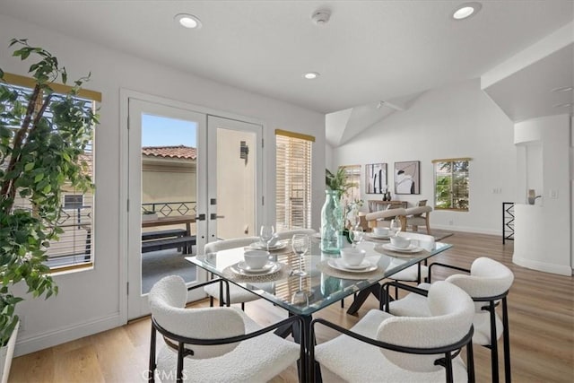 dining area with light hardwood / wood-style floors, lofted ceiling, and french doors