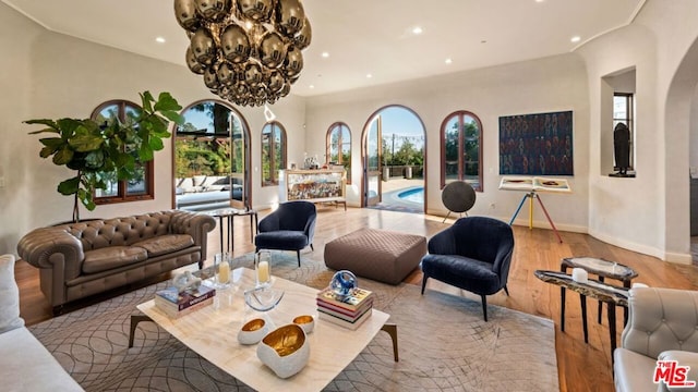 living room featuring a wealth of natural light, a notable chandelier, and light wood-type flooring