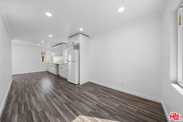 unfurnished living room featuring sink, dark hardwood / wood-style floors, and ornamental molding