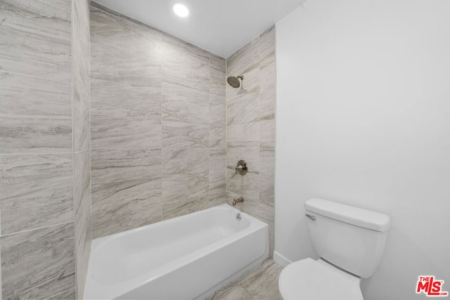 bathroom featuring tiled shower / bath combo and toilet