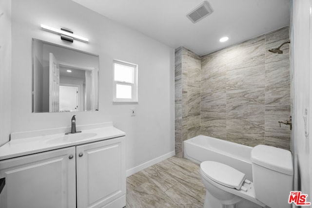 full bathroom with tiled shower / bath, vanity, and toilet