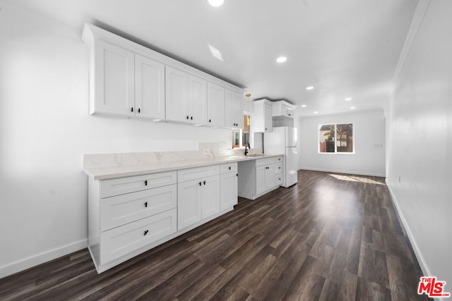 kitchen featuring dark wood-type flooring, white cabinets, white fridge, crown molding, and light stone countertops