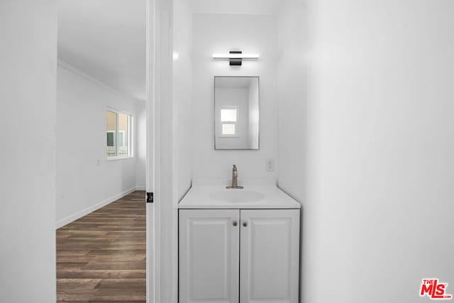 bathroom with crown molding, vanity, and hardwood / wood-style floors