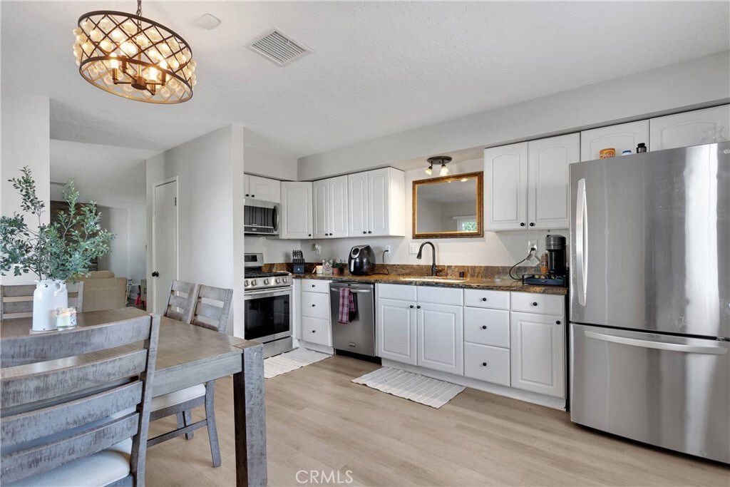 kitchen featuring white cabinets, pendant lighting, sink, appliances with stainless steel finishes, and light hardwood / wood-style floors