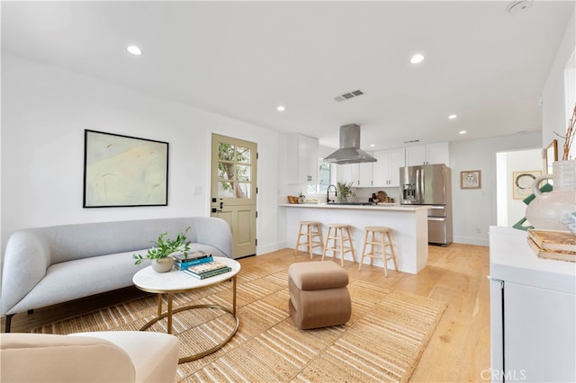 living room with light hardwood / wood-style flooring and sink