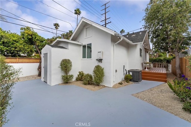 view of home's exterior with central AC, a wooden deck, and a patio