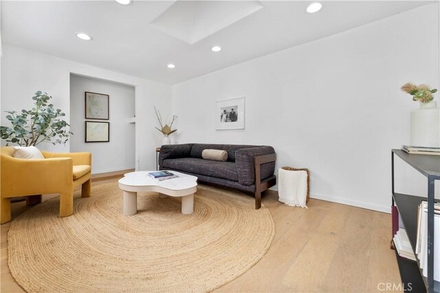 living room with a skylight and light hardwood / wood-style flooring