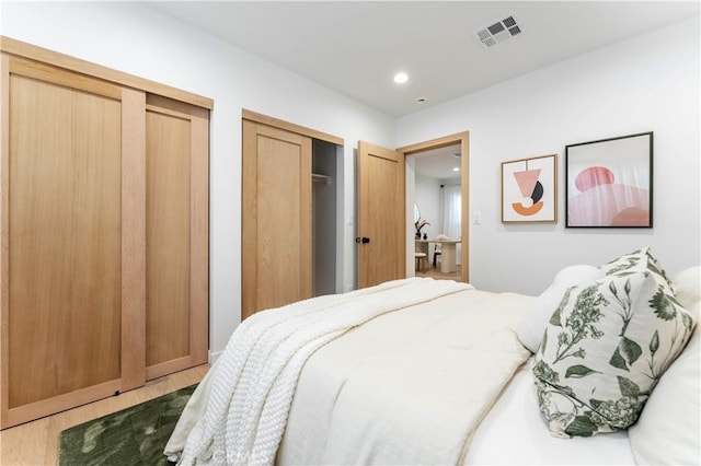 bedroom with hardwood / wood-style floors and two closets