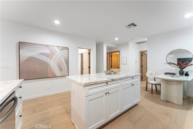 kitchen featuring white cabinets, light wood-type flooring, a kitchen island, and dishwasher