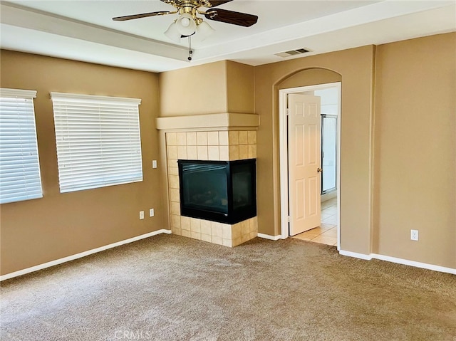 unfurnished living room featuring ceiling fan, light colored carpet, and a tiled fireplace