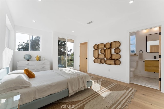 bedroom featuring access to outside, ensuite bath, and light hardwood / wood-style floors