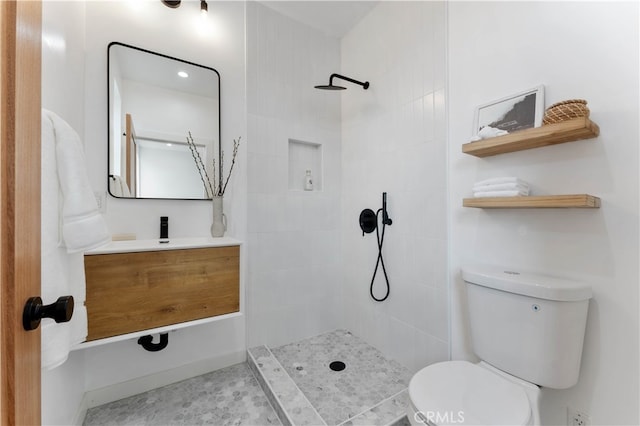 bathroom featuring toilet, vanity, and tiled shower